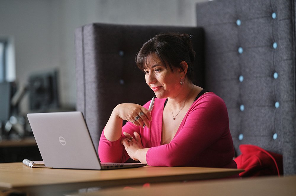 A delegate using a laptop to attend an online event,