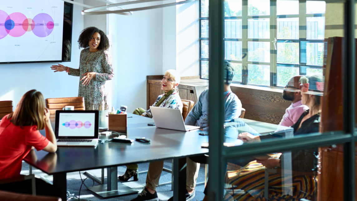 A digital leader in spacious meeting room, presenting to colleagues.