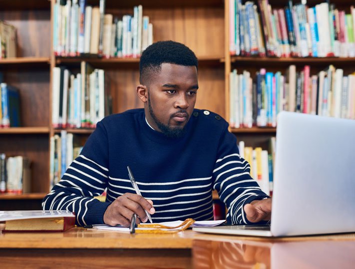 Man using a laptop in a library.